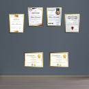 Golden custom diploma frames displaying certificates arranged in a collage on a gray wall above a wooden floor. - Diploma/ Certificate Frames A4 Size - Black / Pack of 2 - Frame World
