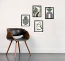 Set of 4 black frames with abstract green and beige art collage on white wall above modern wooden chair with black leather. - Set of 4 Abstract Art Frame set - 8x12" / Black - Frame World