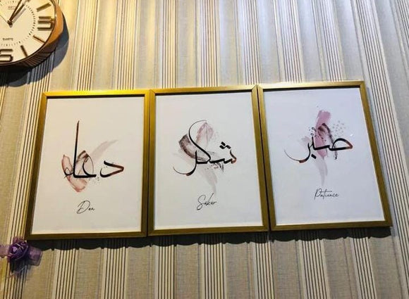 Three gold-framed Islamic calligraphy art prints with the words Dua, Shukar, and Patience on a striped wall.