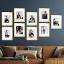 A set of A4 picture frames with glass front displayed above a brown sofa, arranged in a collage style.