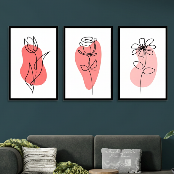 Three abstract floral prints on a dark wall above a gray sofa with decorative pillows.