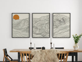 Three framed abstract artworks on a wall above a dining table.