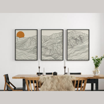 Three framed abstract artworks on a wall above a dining table.