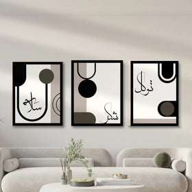 Three framed abstract art pieces with Arabic calligraphy on a wall above a sofa.