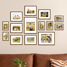 A set of various sized picture frames arranged in a collage on a wall 