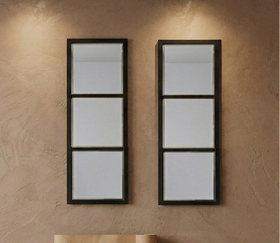 Two wall-mounted mirrors with black frames on a textured beige wall.