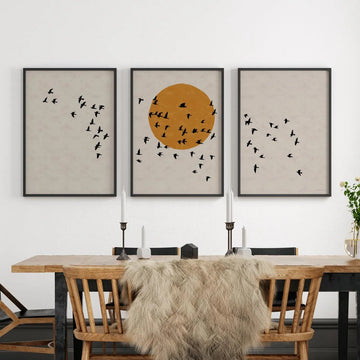 Dining room with wooden table, chairs, and wall art featuring birds and a sun.
