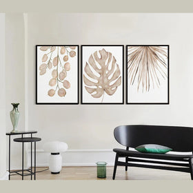 Three framed botanical prints on a wall above a black sofa.