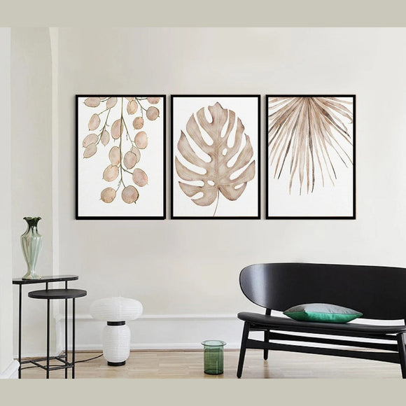 Three framed botanical prints on a wall above a black sofa.