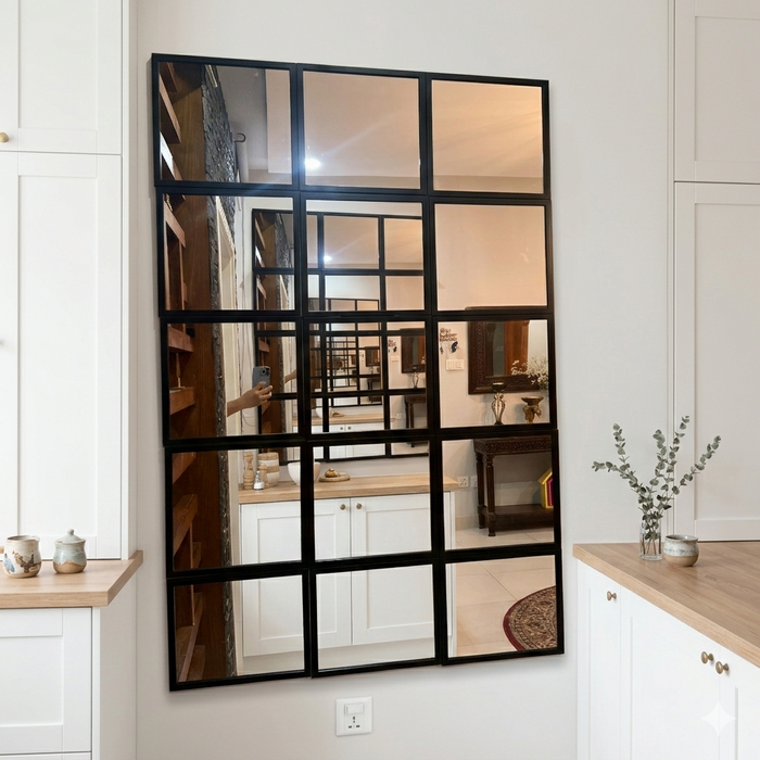Large wall mirror with black metal frame in a room with white cabinets and wooden countertops.