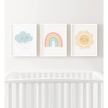 Three colorful prints of a cloud, rainbow, and sun above a crib on a white wall.