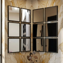 Decorative wall with a grid of square mirrors and a vase with flowers on a marble ledge.
