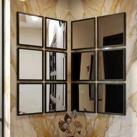 Decorative wall with a grid of square mirrors and a vase with flowers on a marble ledge.