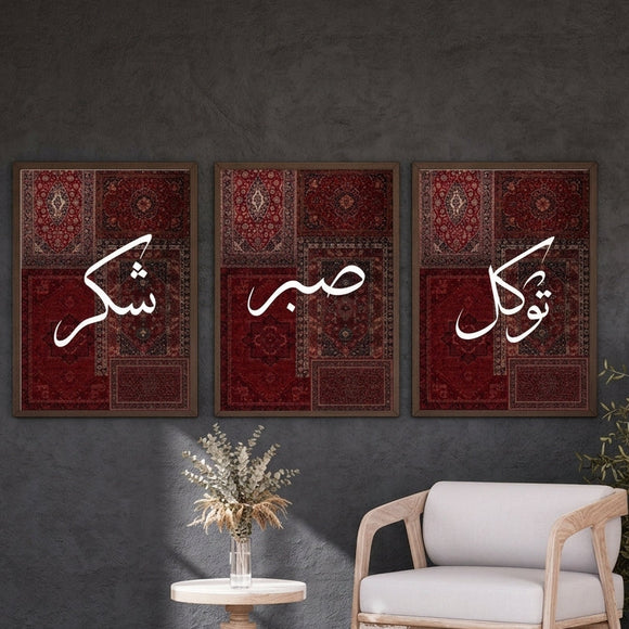 Three framed wall art panels with white Arabic calligraphy over deep red patterned rug designs, displayed in a styled interior with a chair, side table, plant, and pendant light against a dark gray wall.