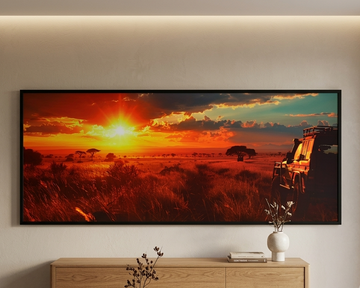 A large framed wall art print depicting a dramatic African savanna sunset with an orange sun low on the horizon, red and yellow clouds, and a safari vehicle on the right, displayed in a modern living room above a light wood console table.